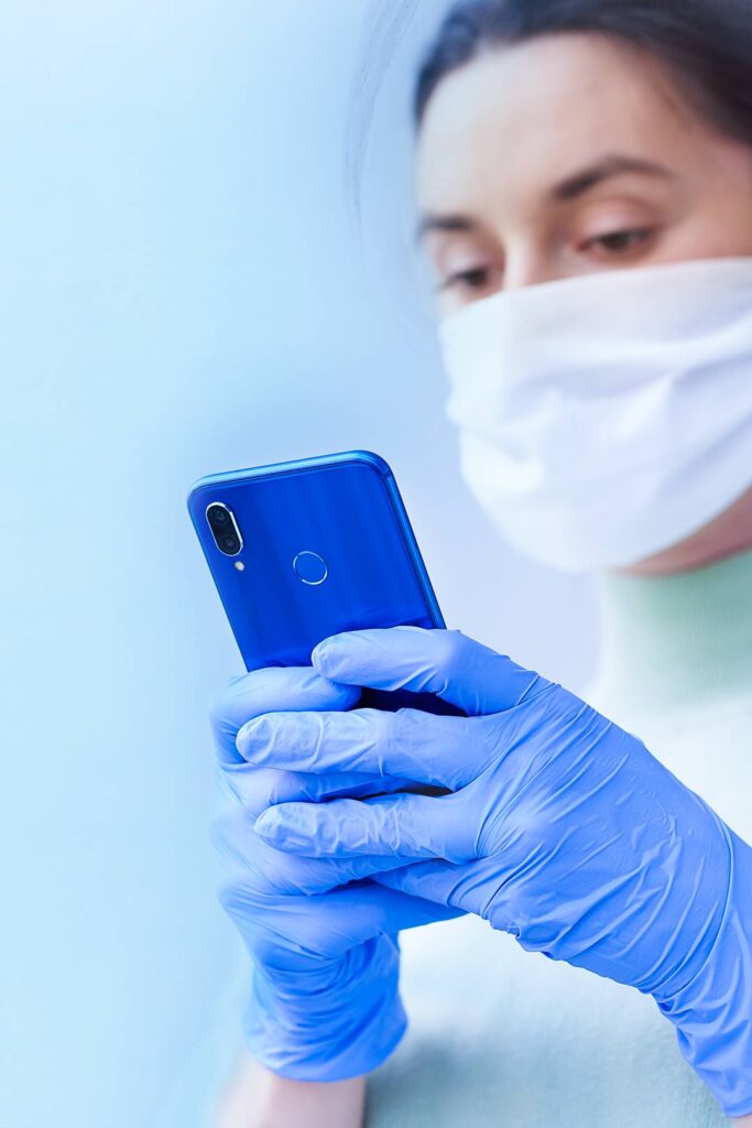 Woman with face mask and gloves looking at her phone