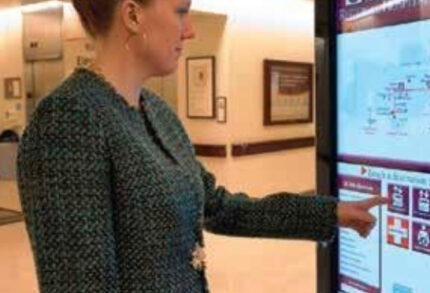 Woman interacting with touchscreen kiosk