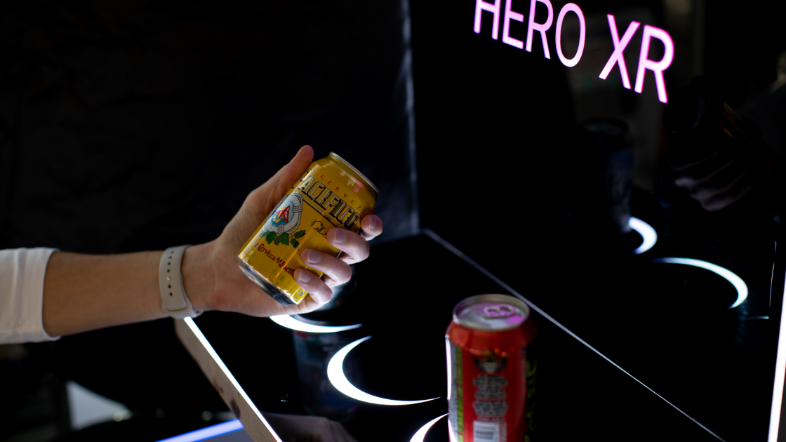 Person picking up a drink from a Hero XL retail sign shelf